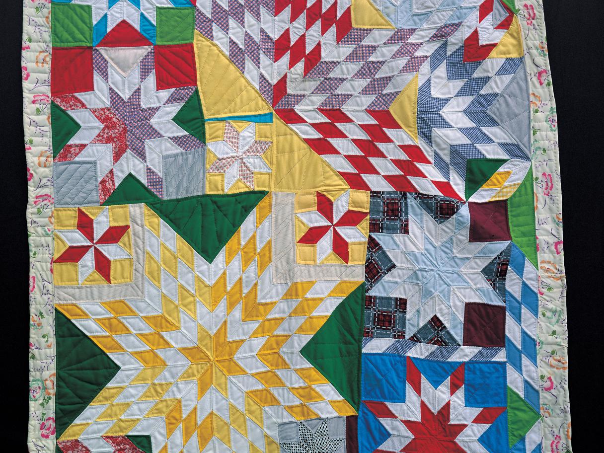 A quilt made with primary colored triangle forming stars