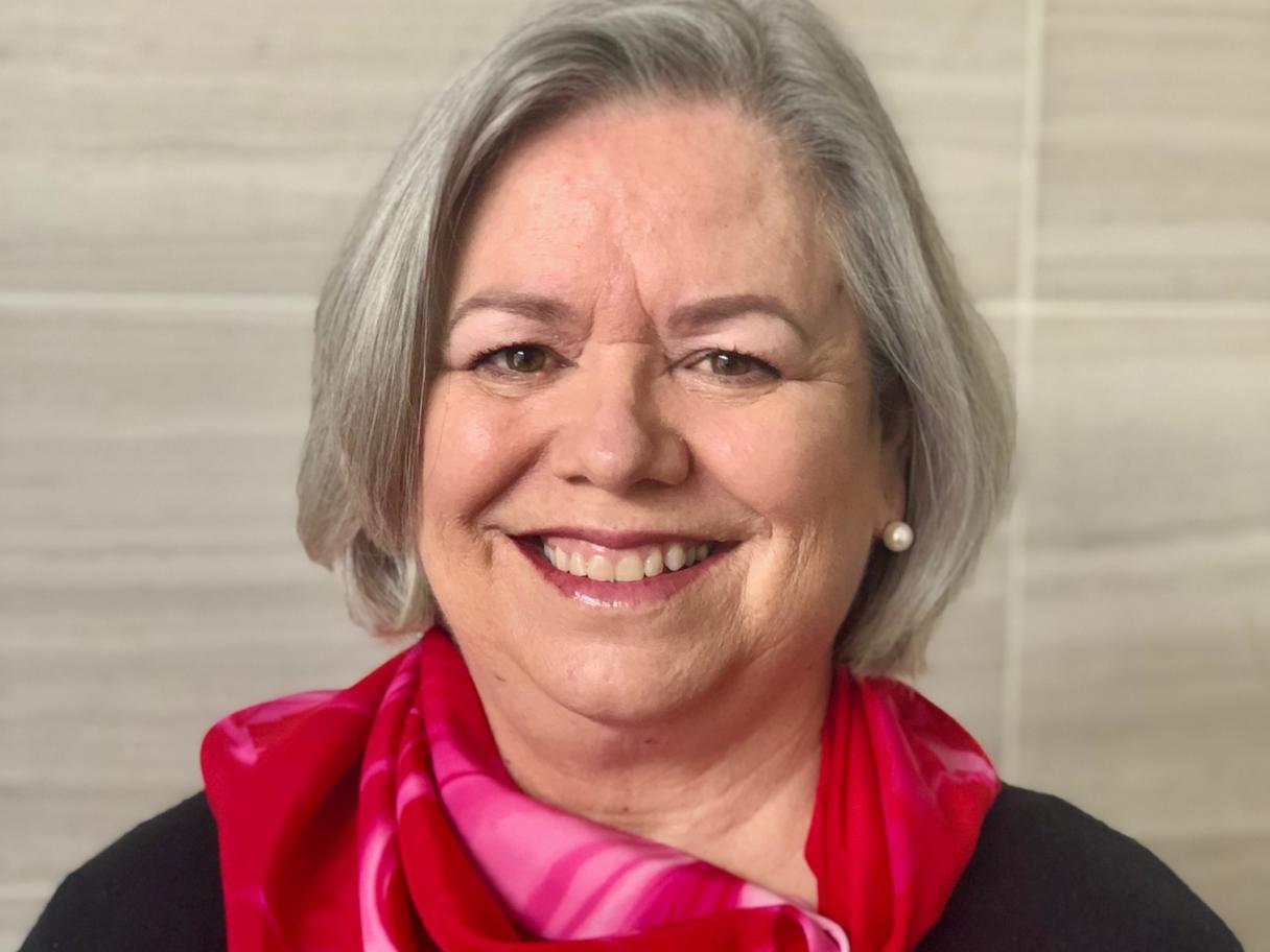 Deborah Bradford has shoulder length gray hair and is wearing red and pink scarf
