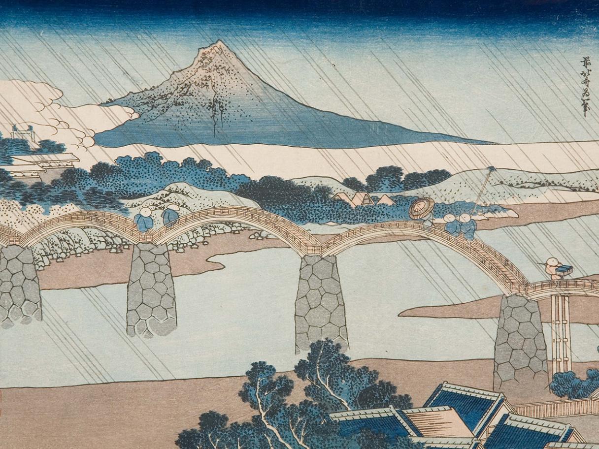 Japanese woodblock print of a river with a stone bridge and Mount Fugi in the background