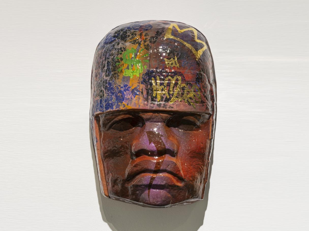 Horacio Rodriguez Salt 15 Colossal Head A brown ceramic mask in the style of ancient Meso-American art covered in modern-day graffiti
