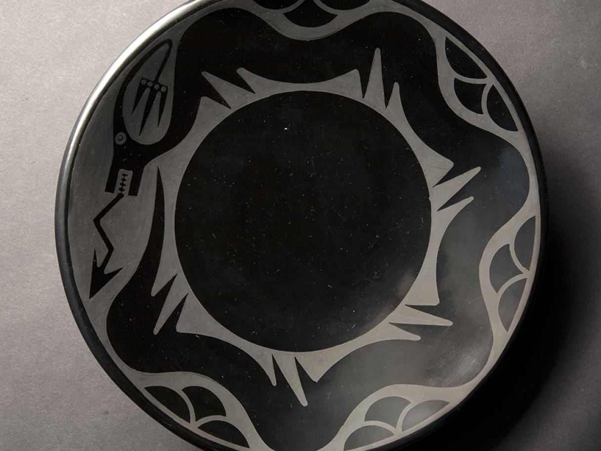 black and gray ceramic plate with an abstract serpent circling the edge