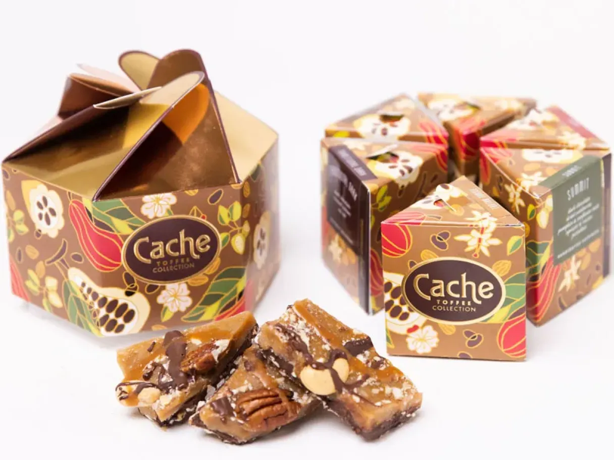 two hexagon shaped boxed of Cache toffee witw a pile to toffee chunks in the front