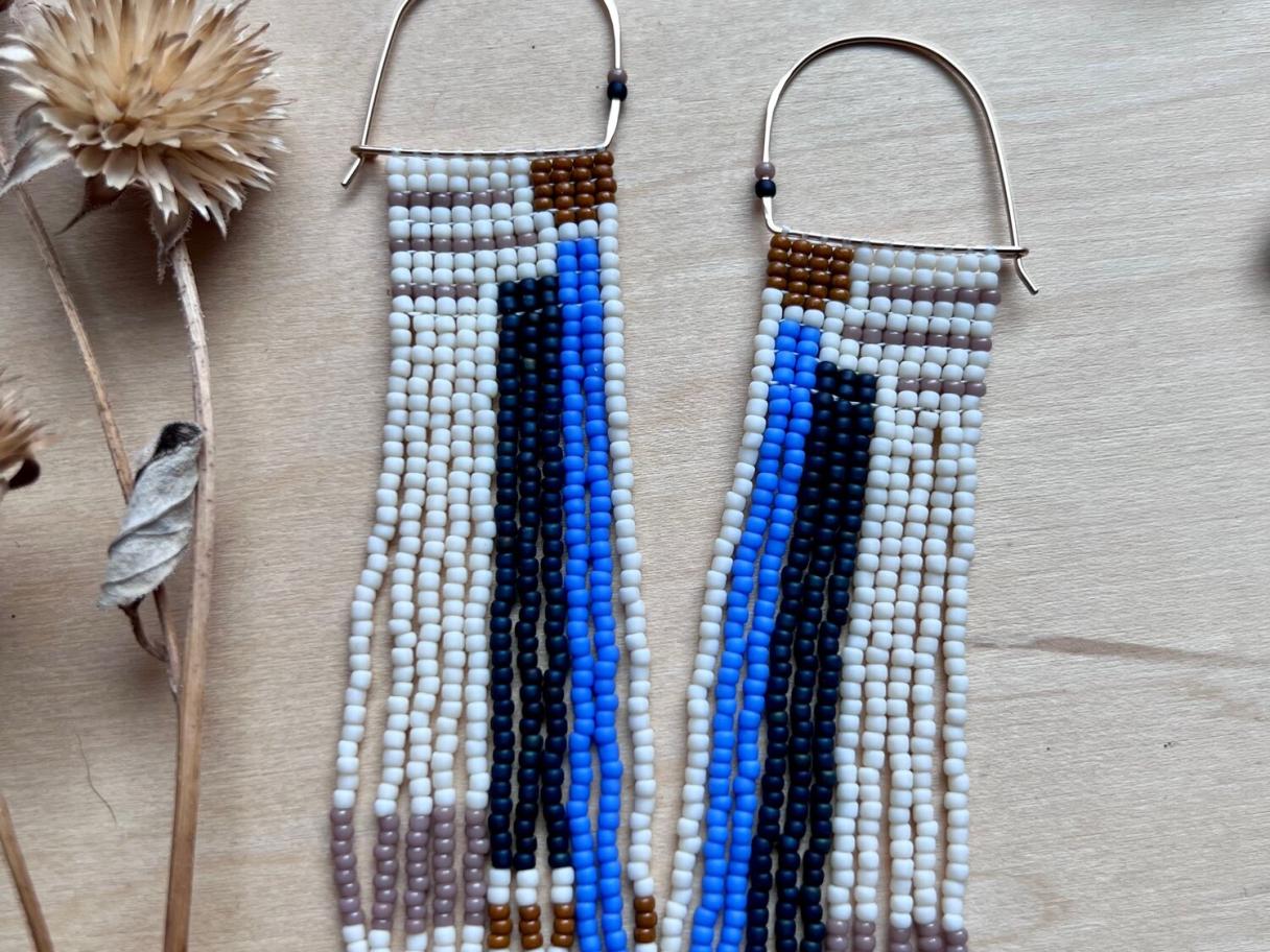 beaded earrings next to a dried flower on a wood table