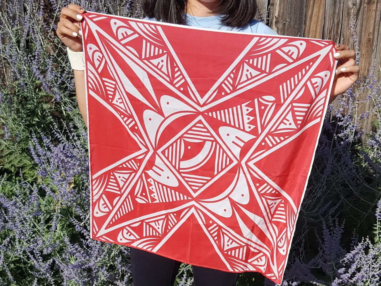 a person is holding up a red and white scarf with southwest pattern on it