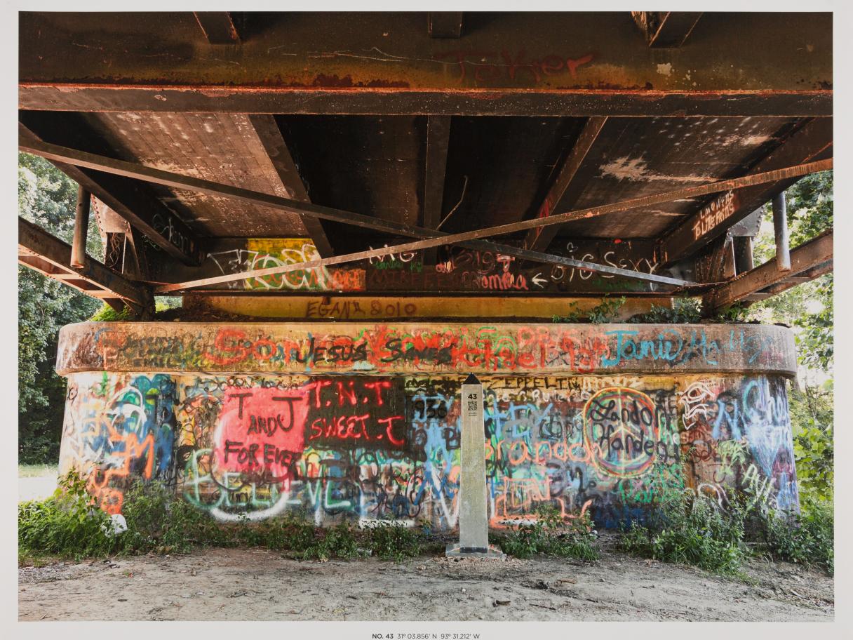 A photo of an obelisk under a bridge with graffiti 