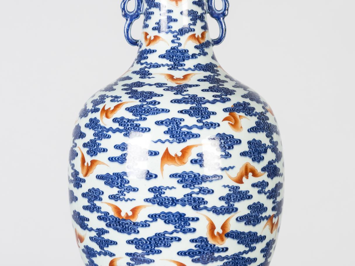 A white and blue vase with orange bats