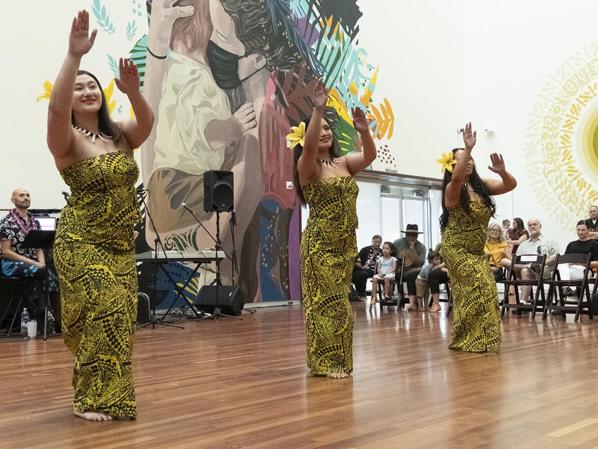 three women in yellow and black traditional Polynesian clothing dancing.