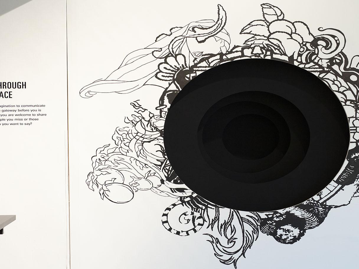 A large black circle on a white wall is surrounded by botanical line drawings.