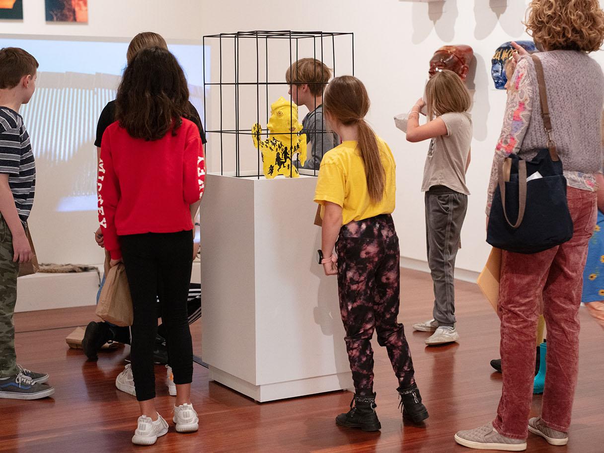A group of children standing in a large room, looking at colorful art