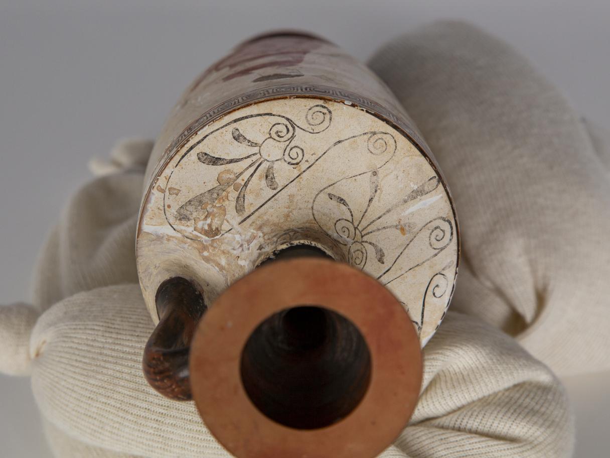 A white and red lekythos tipped on its side.