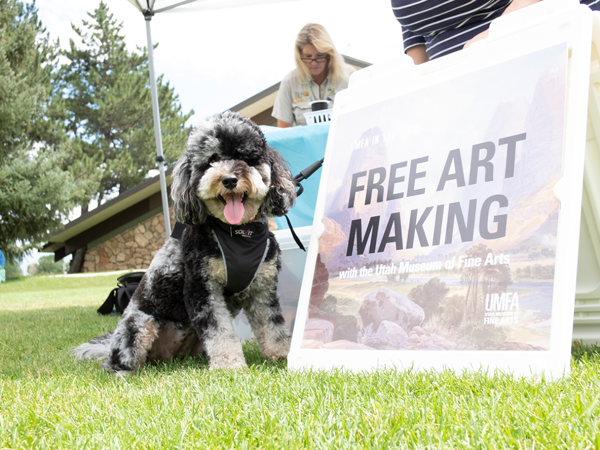 A dog sits next to a sign that reads "Free Art Making".