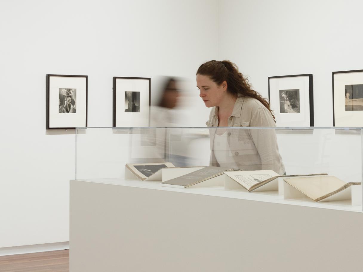 A woman with long, curly hair looks at magazines in a glass display case.