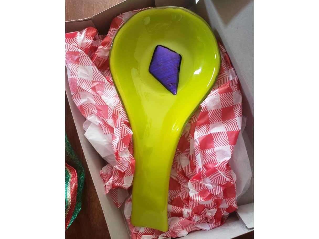 A bright green glass spoon holder with a purple kite-shaped center.