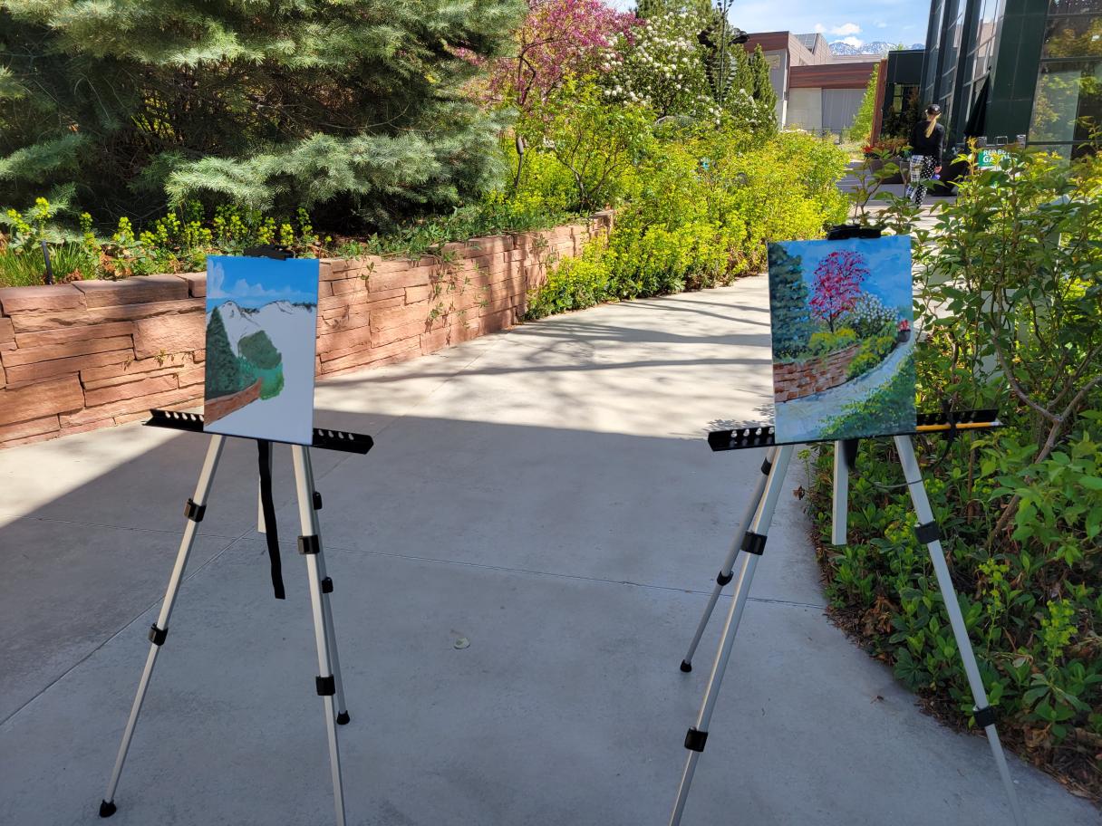 Two easels sitting outside with paintings on them.