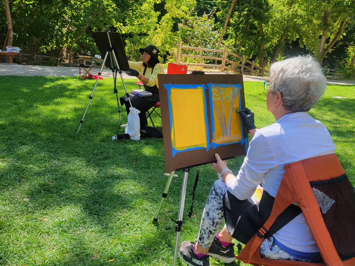 Adults 55 and better sit outside and paint.