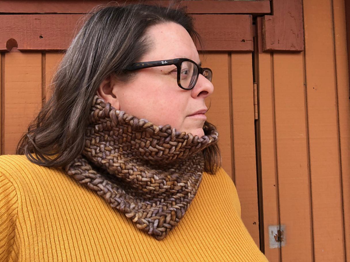 A woman in a yellow shirt models a woven cowl.