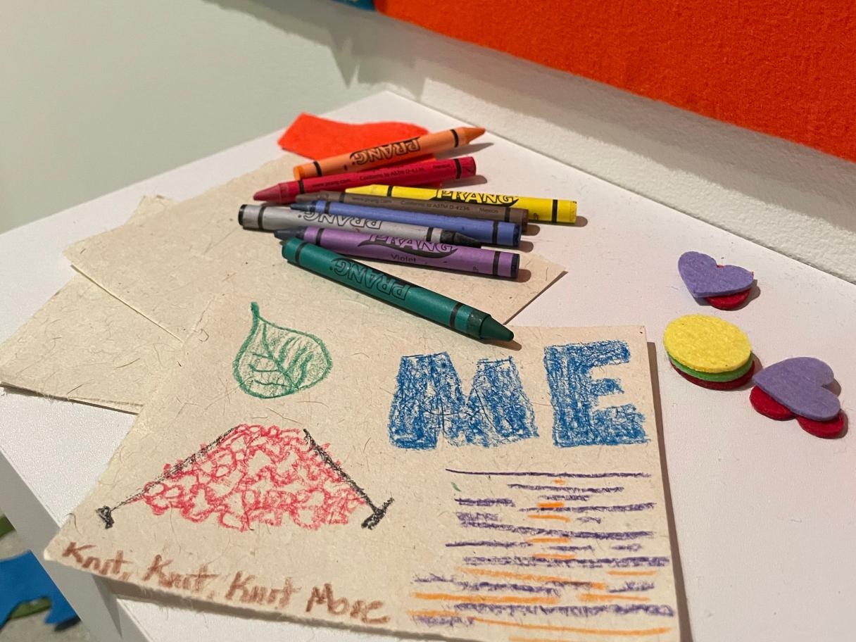 Crayons and seed paper on a table with felt shapes.
