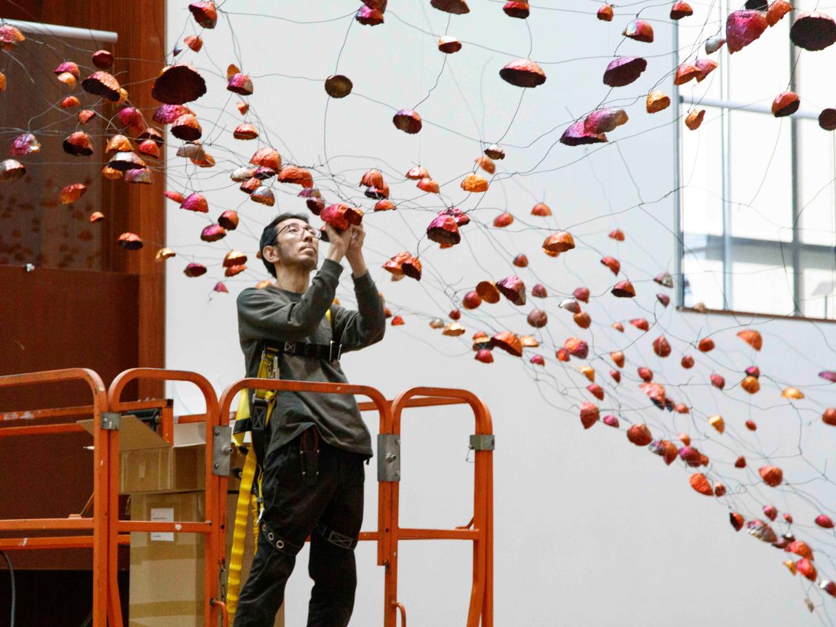Artist Onishi Yasuaki attaches a copper bowl to a net of wires.