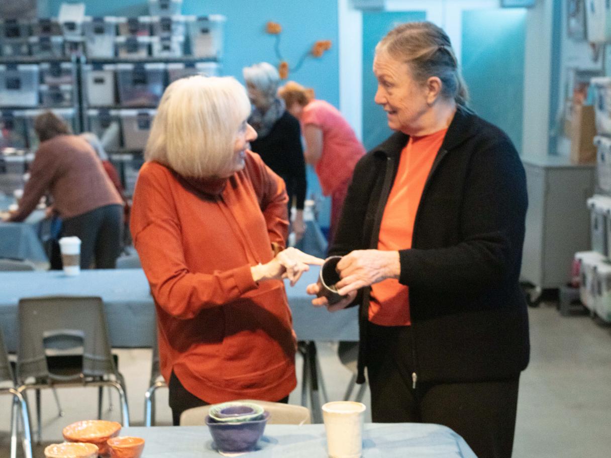 Creative Aging Two people talk surrounded by ceramic dishes.