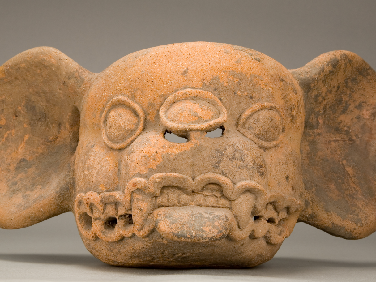 A red ceramic bat head effigy.