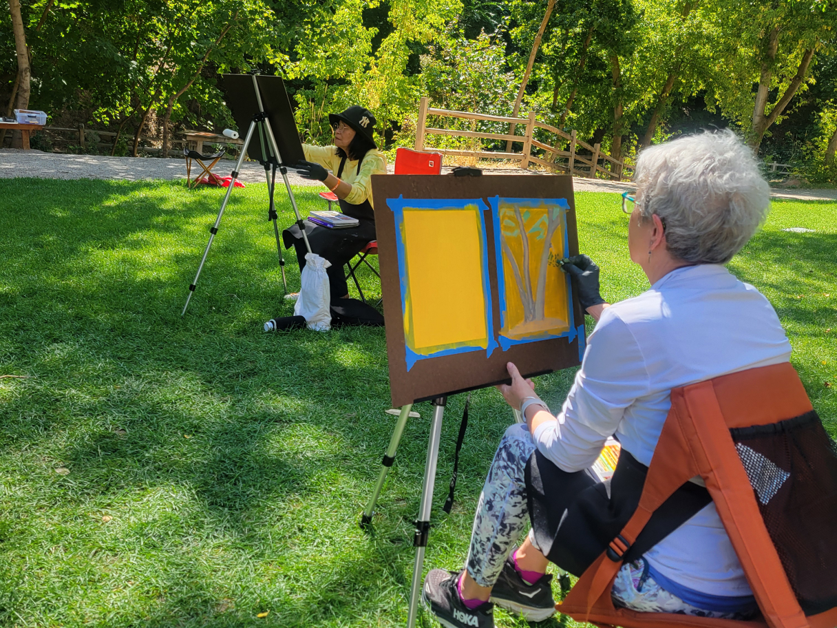Two people paint in a park.