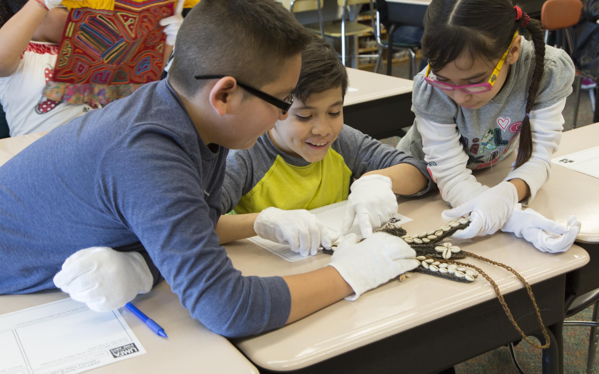 Group of students examine a work of art in a classroom. Group of students examine a work of art in a classroom.
