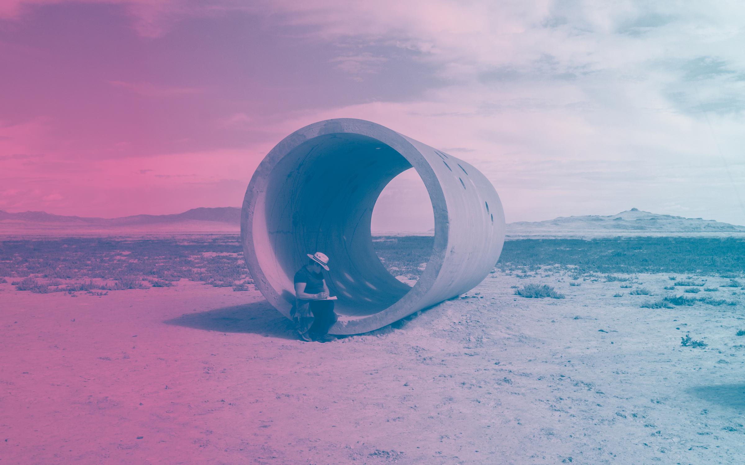 Sun Tunnels meet-up 2019 Sun Tunnels meet-up, woman writing in tunnel wearing sun hat, purple gradient overlay