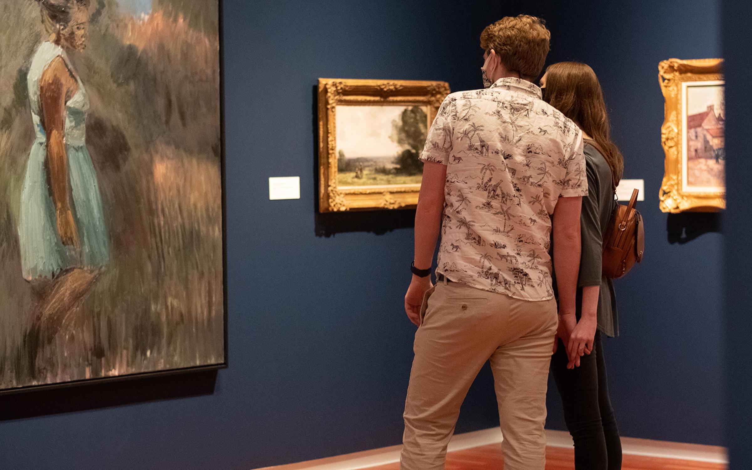 a couple with their back to the camera looks at Periphery, a painting of a woman in a filed in the UMFA European gallery