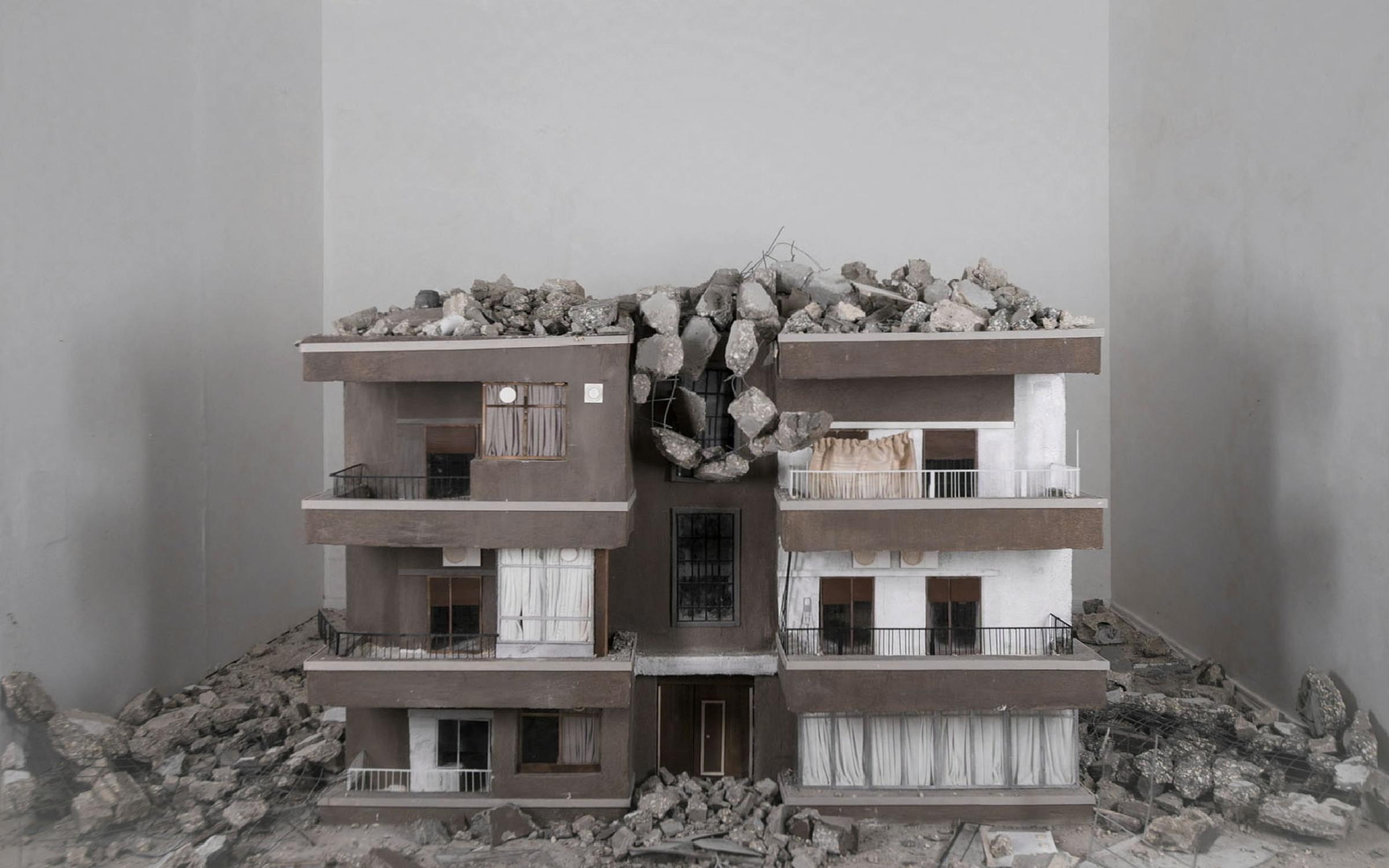 A still from video art by Hrair Sarkissian A concrete replica of a building with rocks on it.