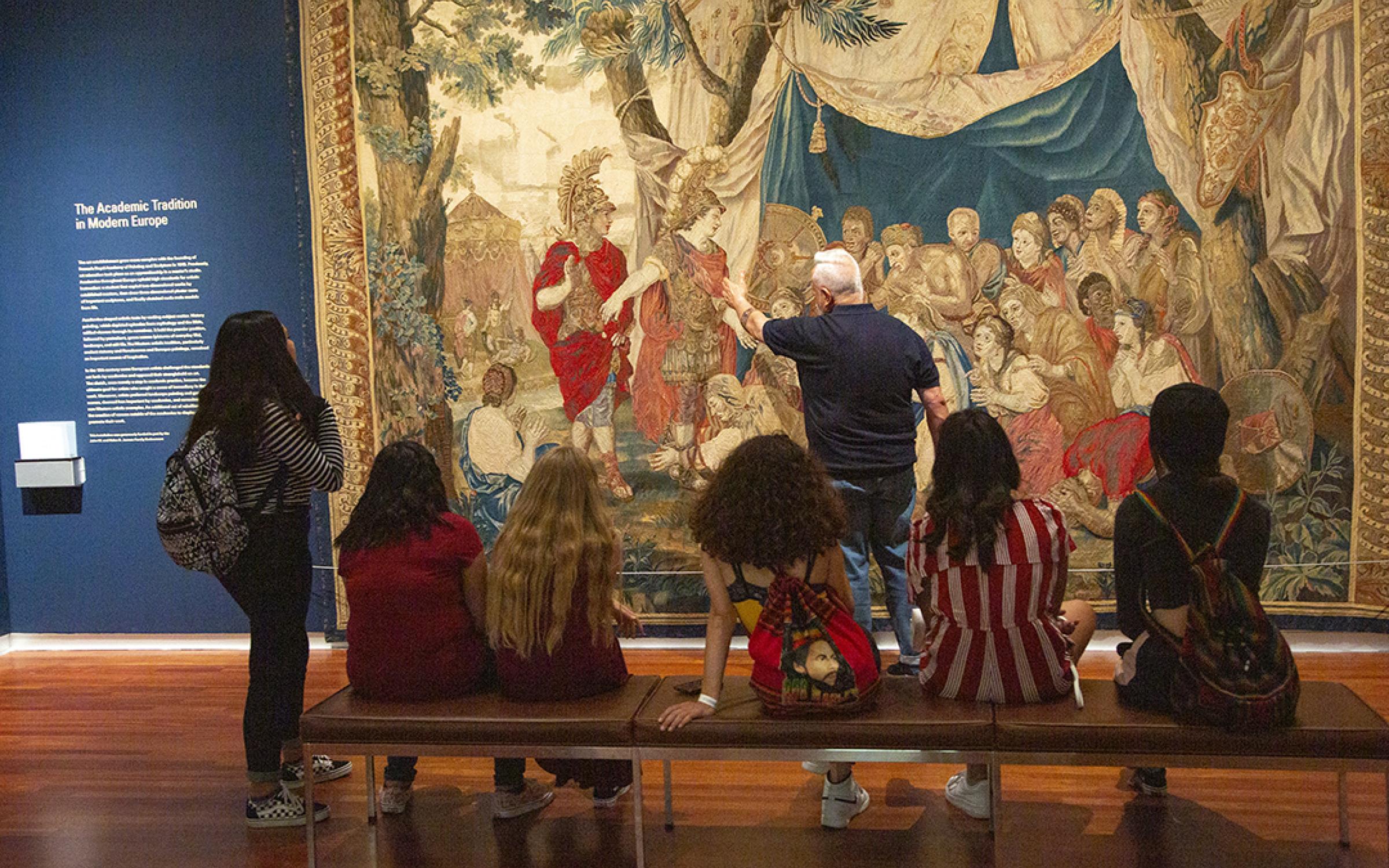 docent given tour to kids in front of tapestry