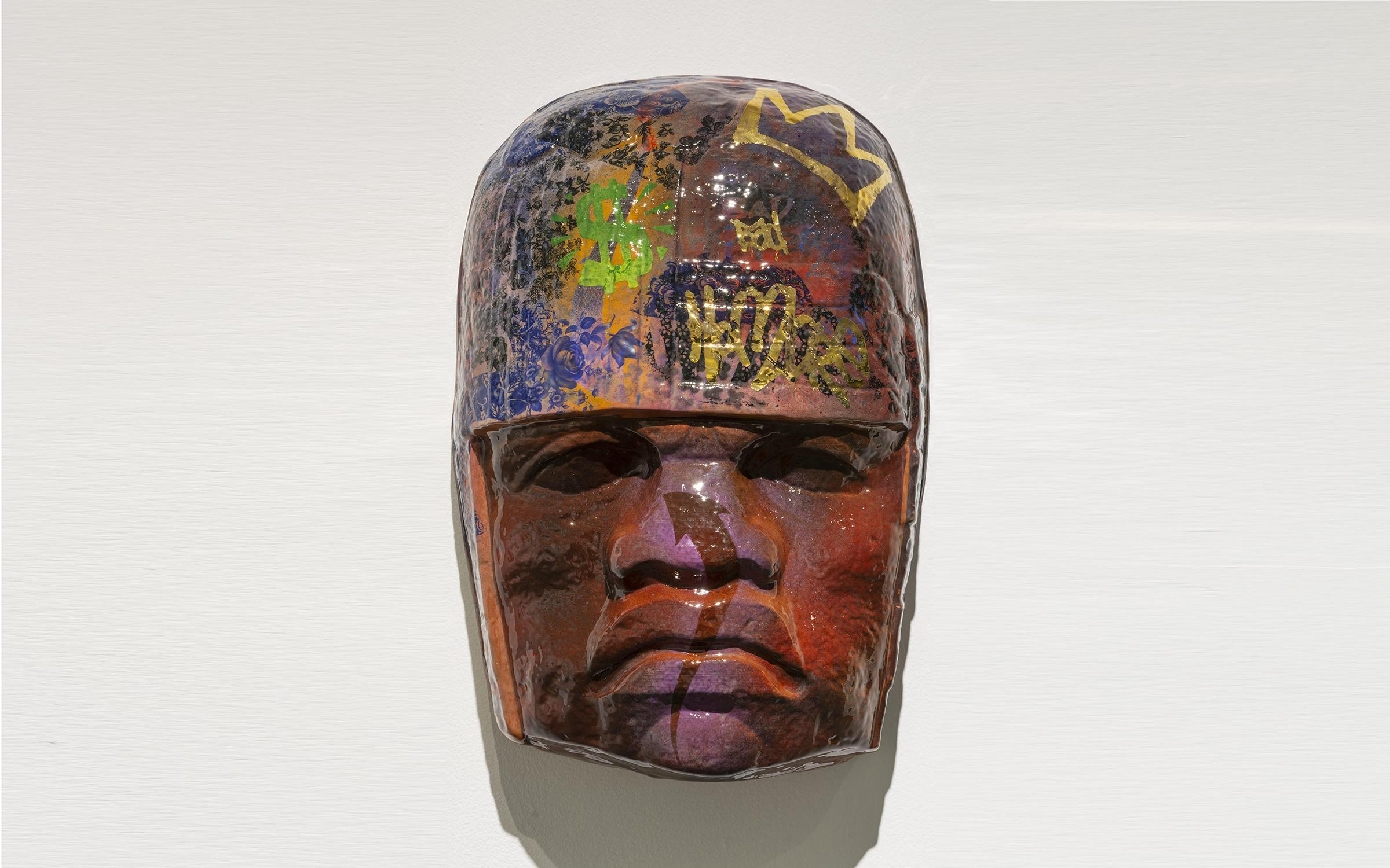 Horacio Rodriguez Salt 15 Colossal Head A brown ceramic mask in the style of ancient Meso-American art covered in modern-day graffiti