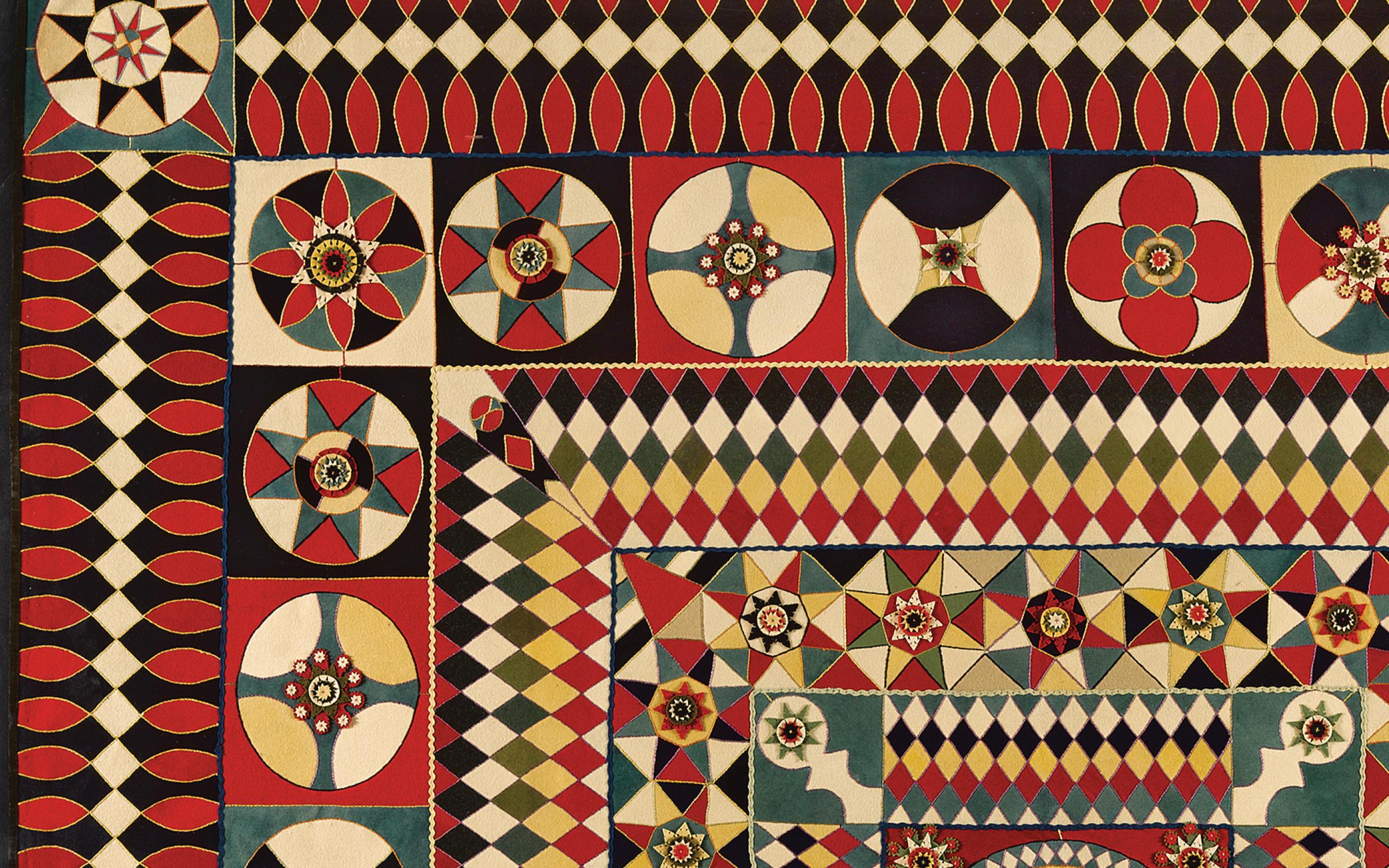 An intricate geometric shaped quilt with red, yellow, and tan.