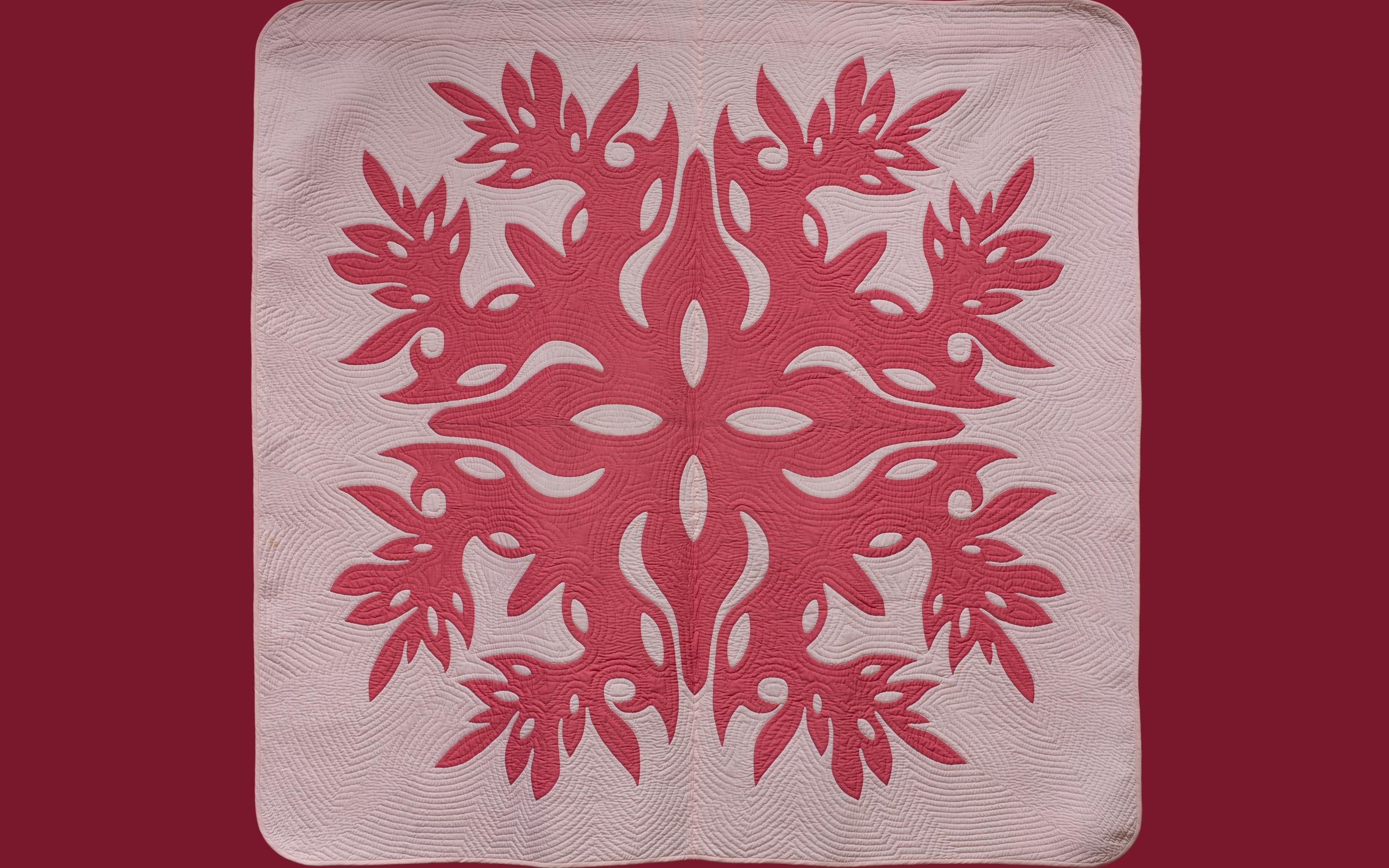 A large pink quilt with hot pink designs on a burgundy background.