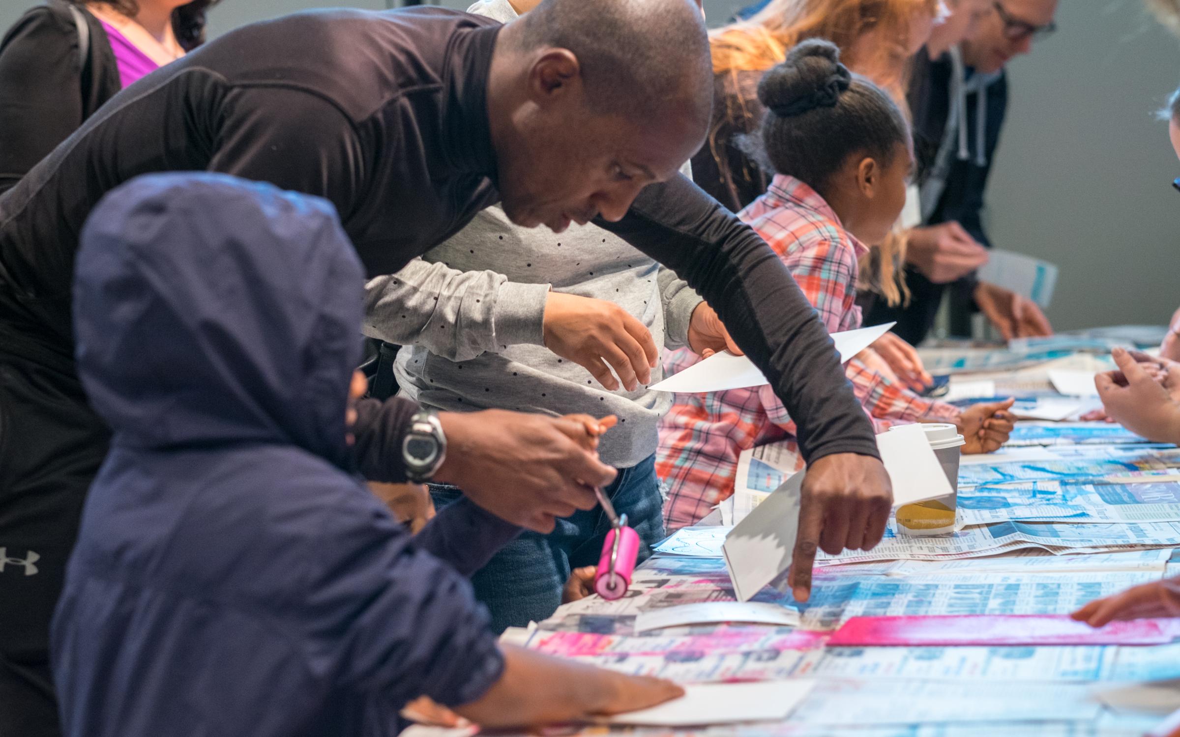 A black father and his son painting prints on newspapers