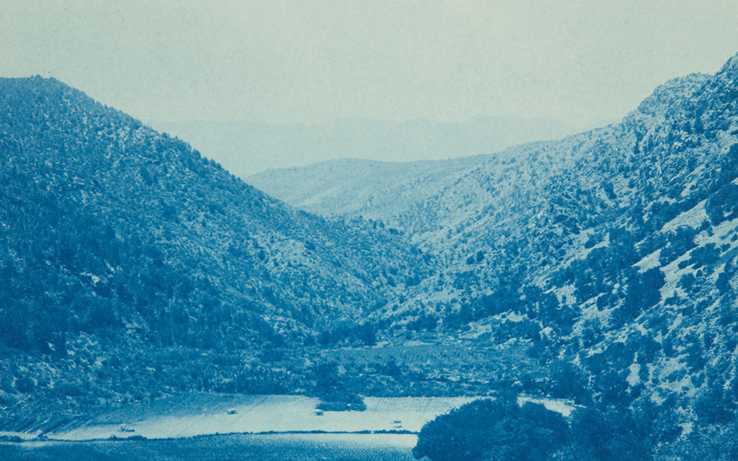 A blue photograph of a mountain valley