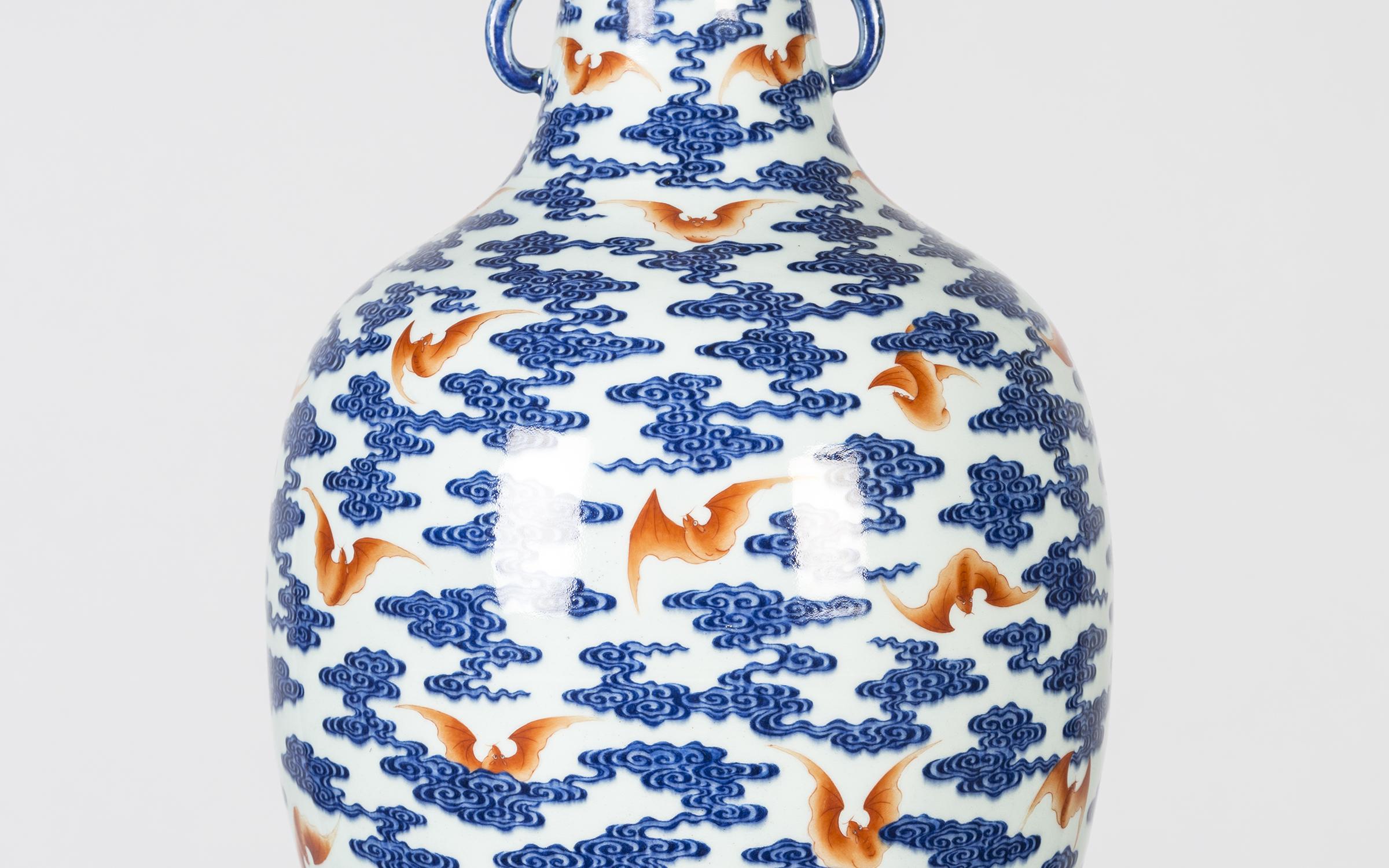 A white and blue vase with orange bats