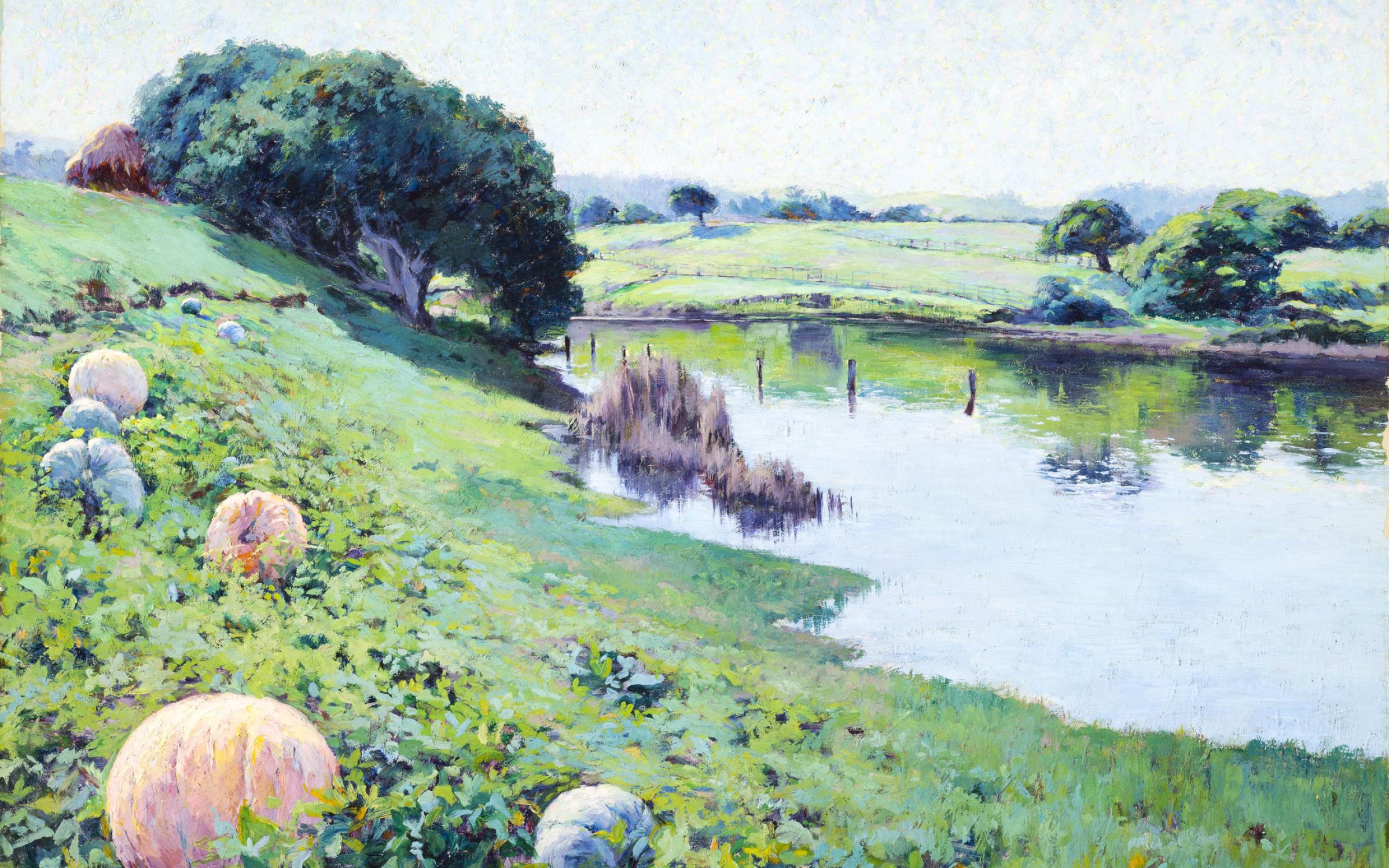 A grassy hill slopes to a shallow pond. Colorful pumpkins dot the foreground.