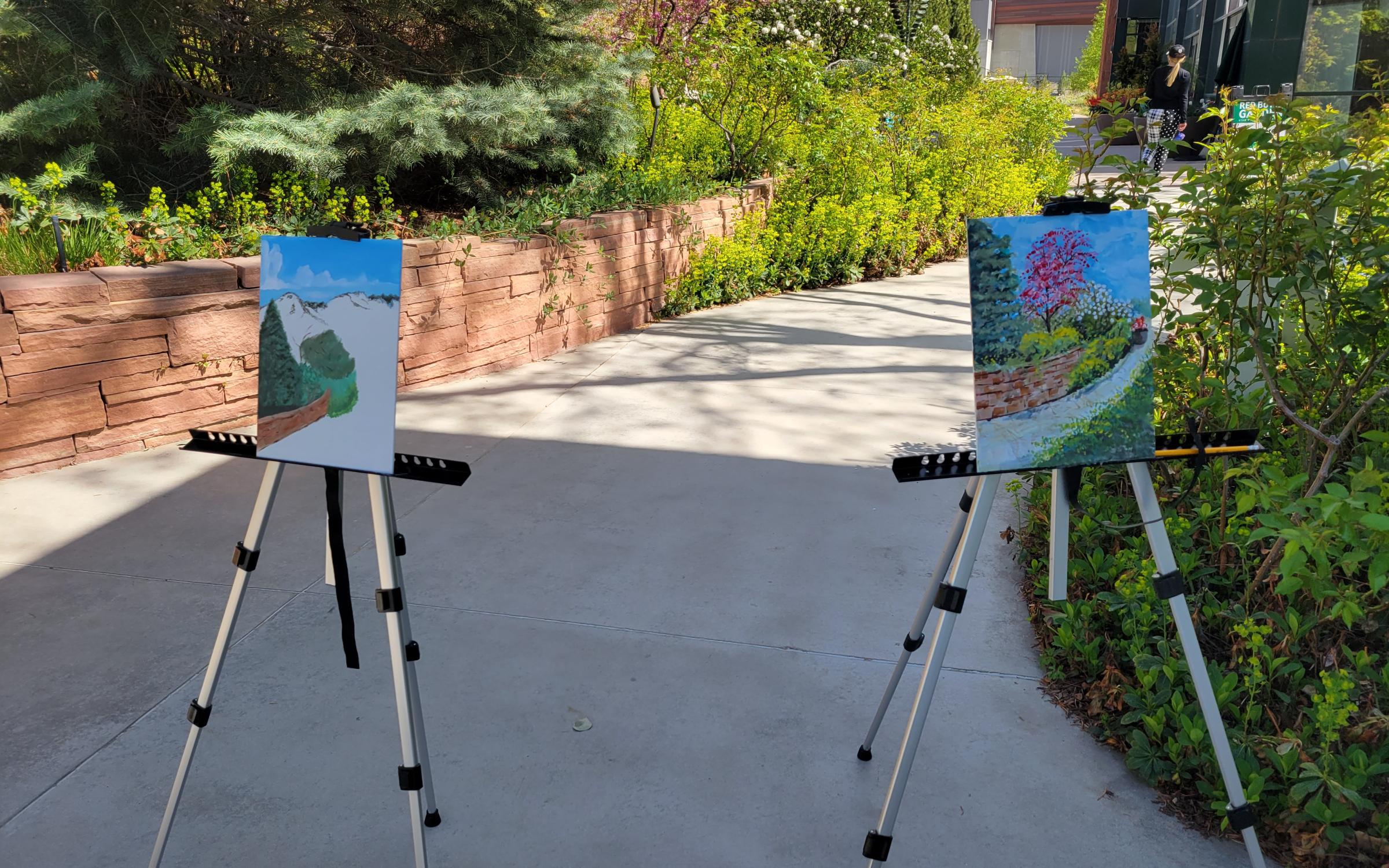 Two paintings on easels set outside.