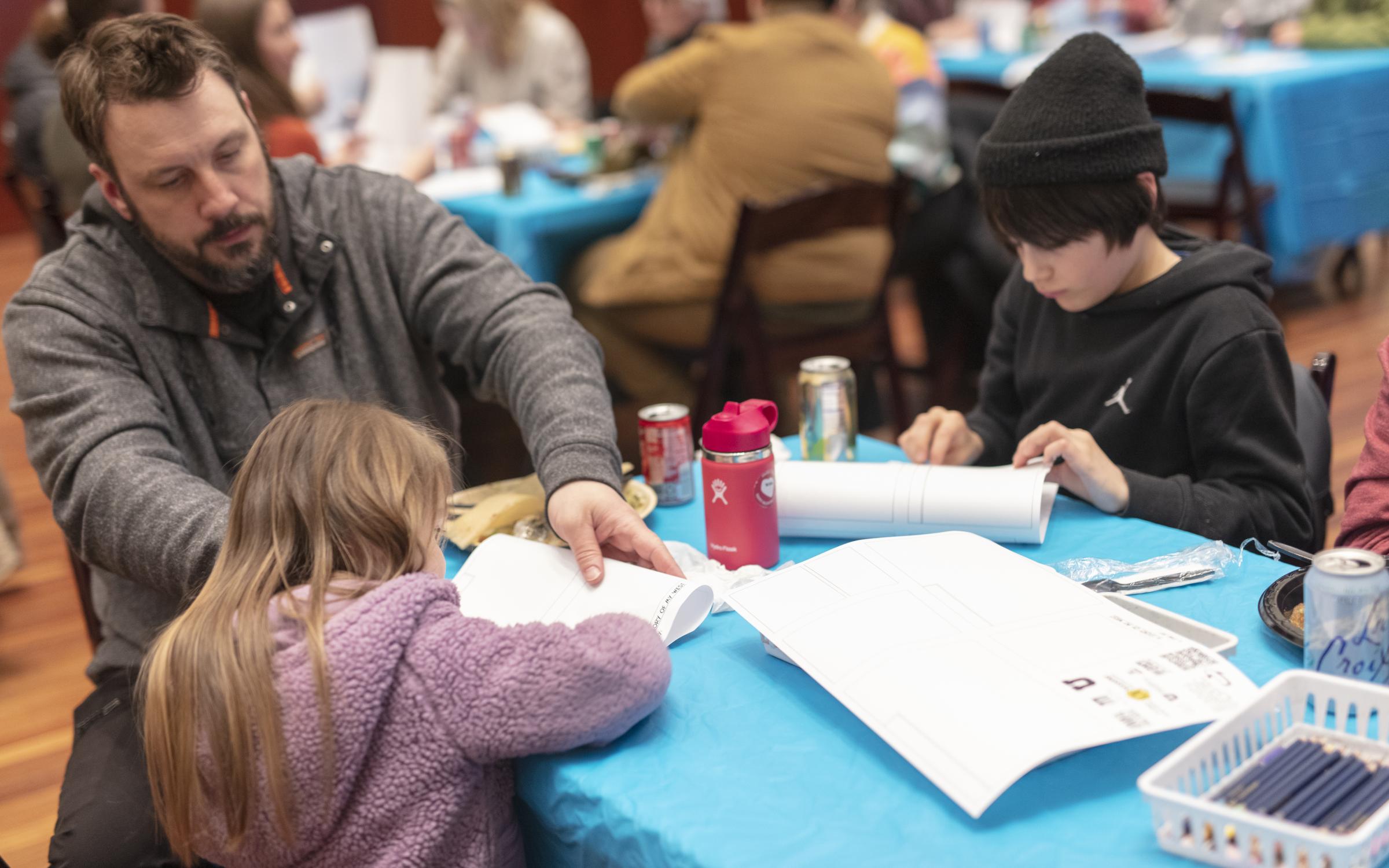 A family fold their homemade comic books.