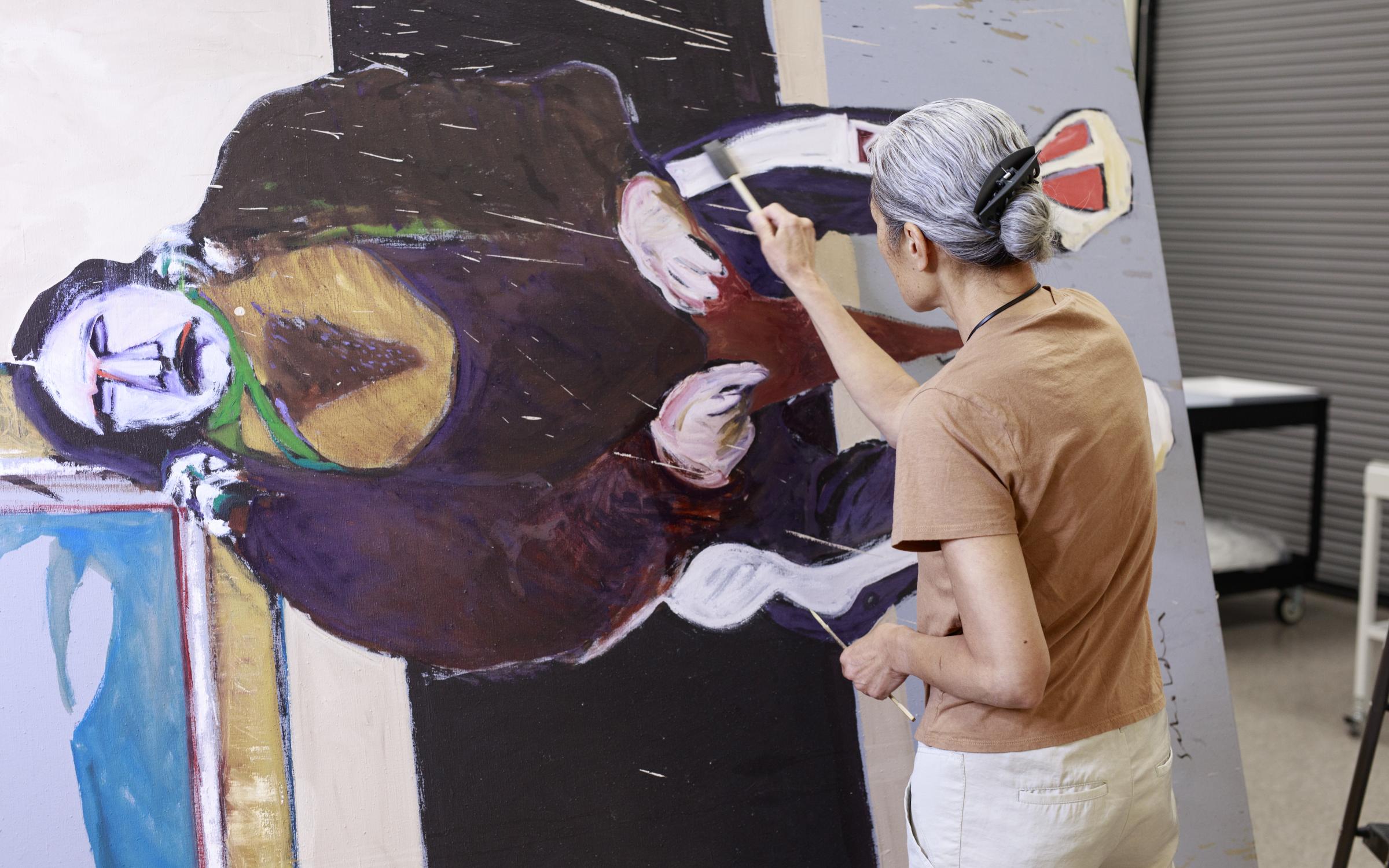 A person carefully cleans a painting.