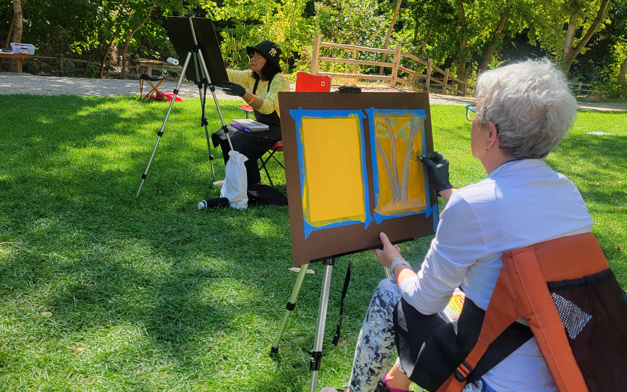 Adults 55 and better sit outside and paint.