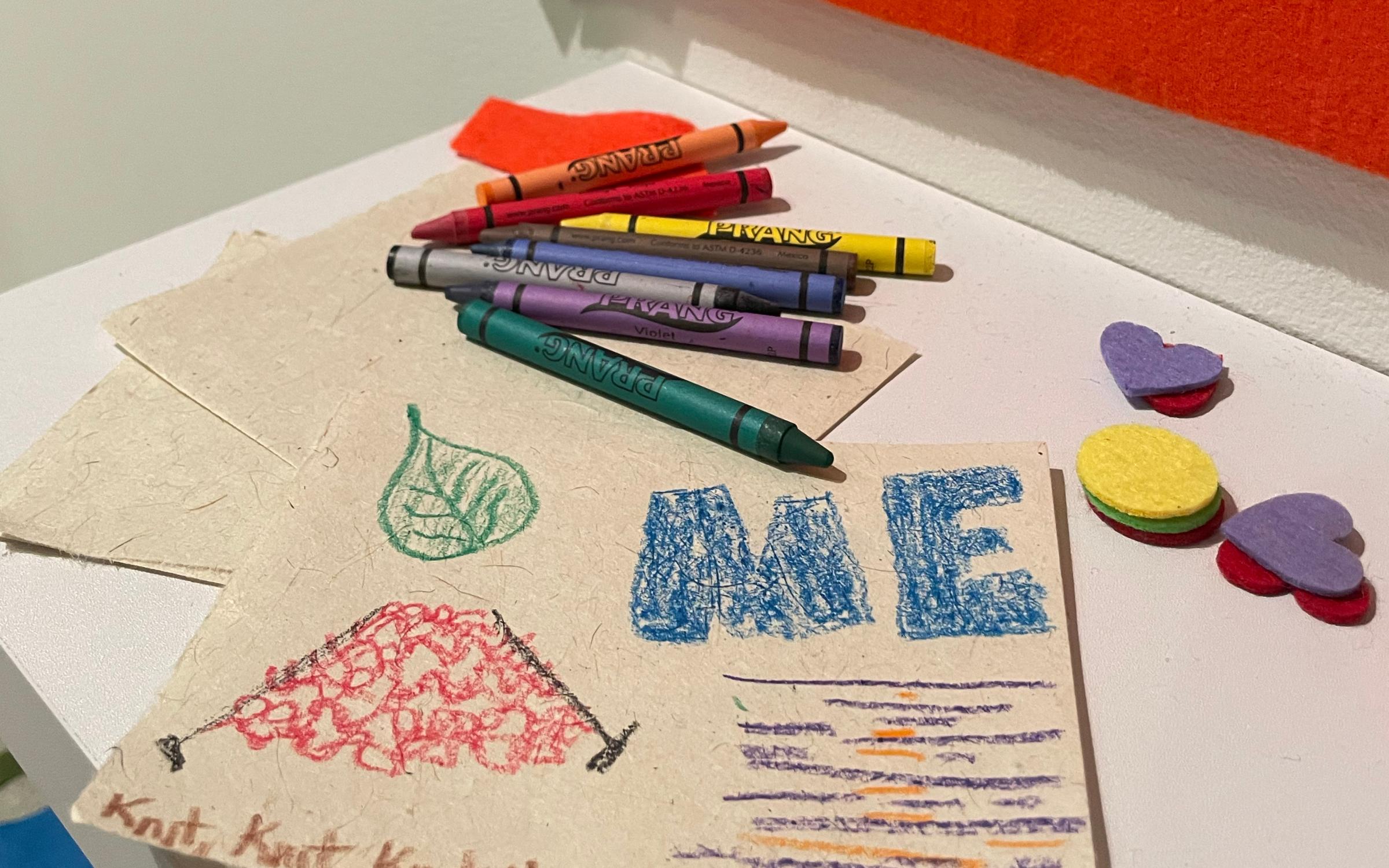 Crayons and seed paper on a table with felt shapes.