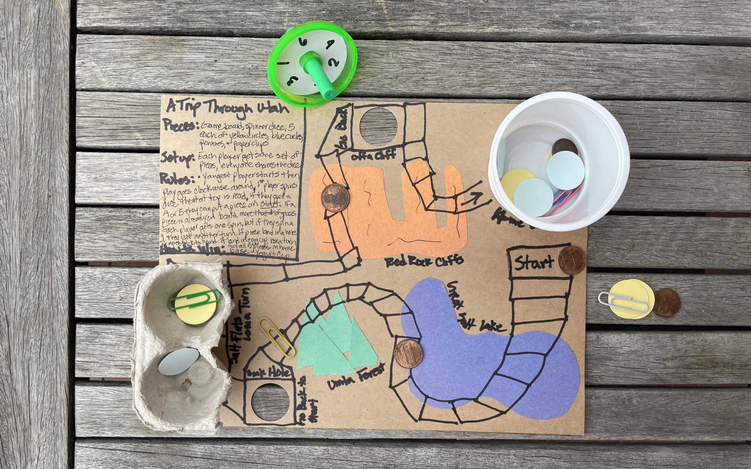 Make Your Own Game A cardboard game board with colorful recycled pieces.