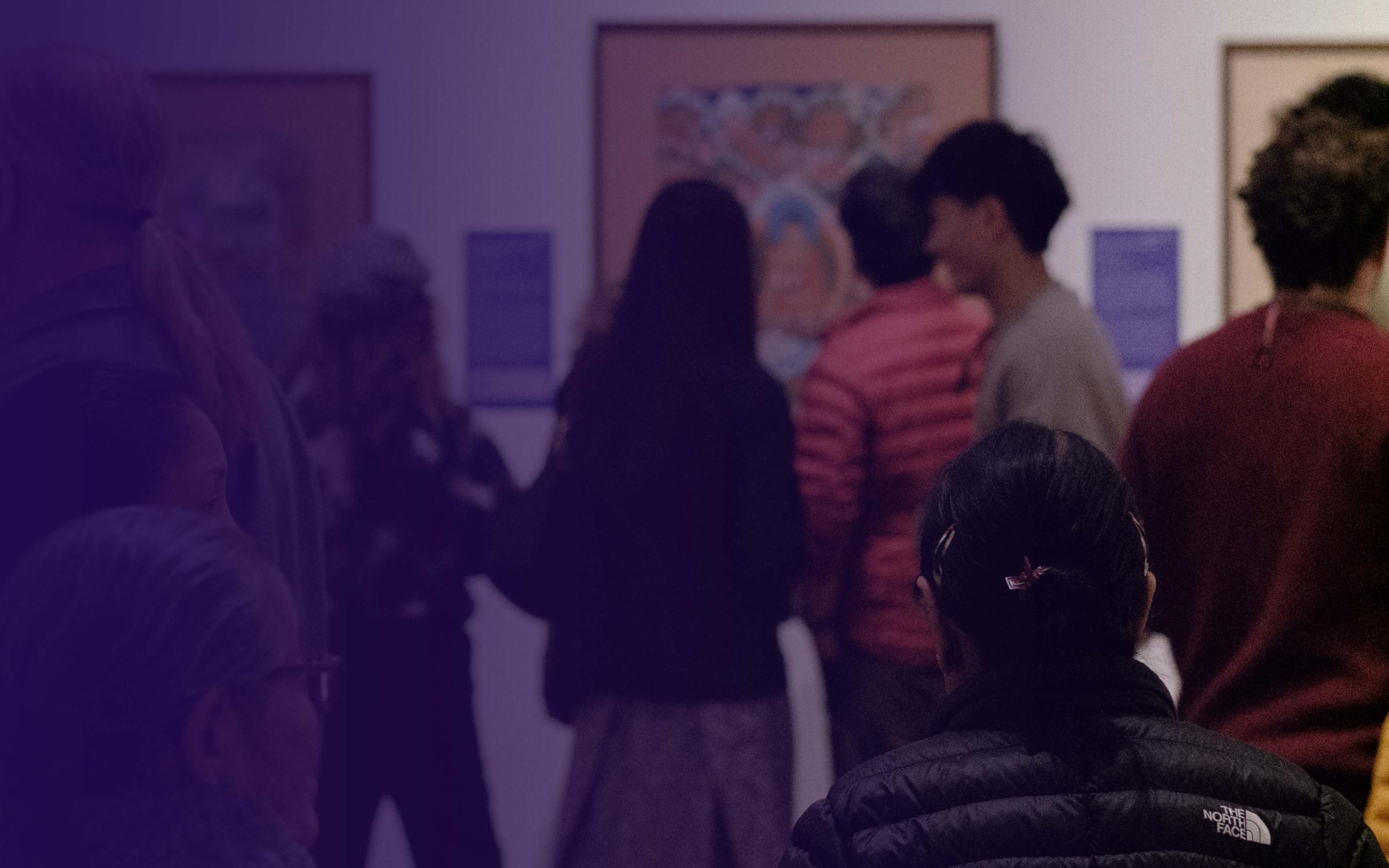 Year of Compassion A photo of people in a gallery with a blue gradient overlaid on top.