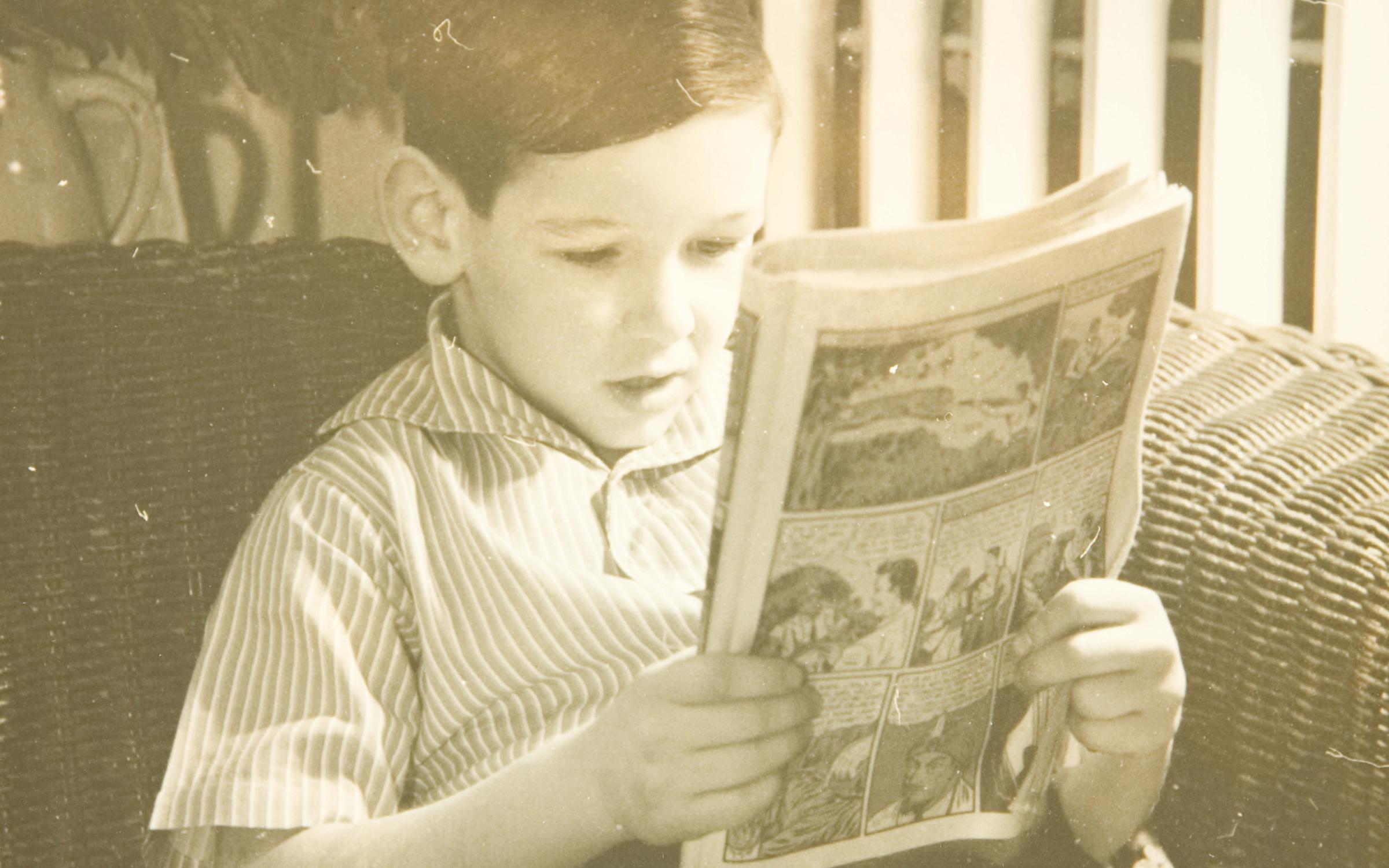 A young boy reads a comic book.