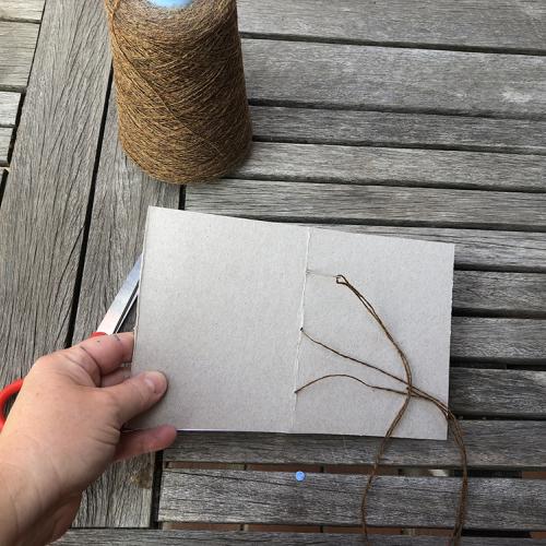 Leaf Rubbing book with the cover facing up twine and needle poking through a hole in the center