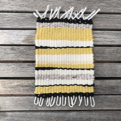 Handmade woven rug made with yellow, gray, white, and black yarn