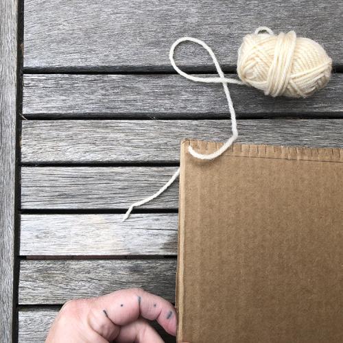 cardboard loom with white yarn