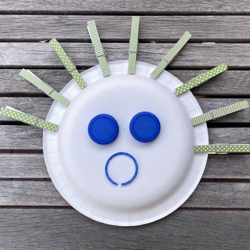 a paper plate mask that looks like it has spiky hair and a surprised look
