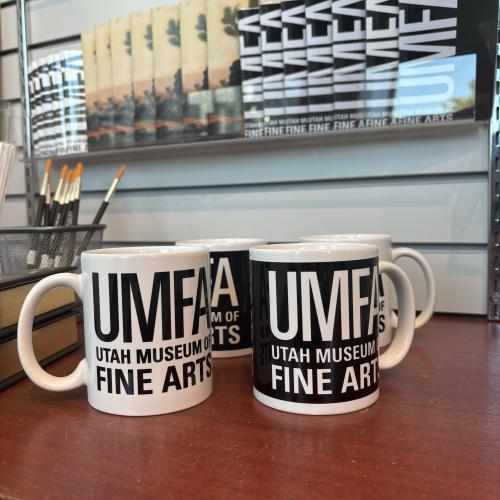 Black and white mugs with the UMFA Utah Museum of Fine Arts logo printed top to bottom.